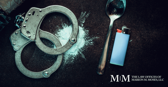 cocaine, handcuffs, spoon, and lighter on black table