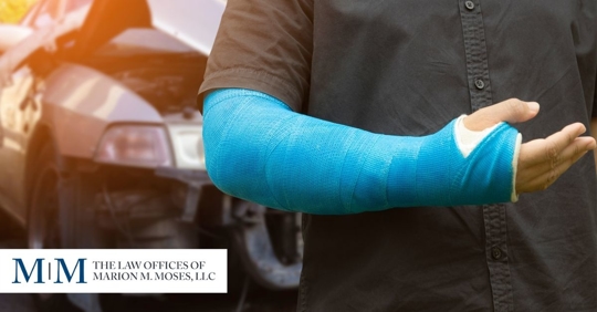arm in cast standing in front of car damage